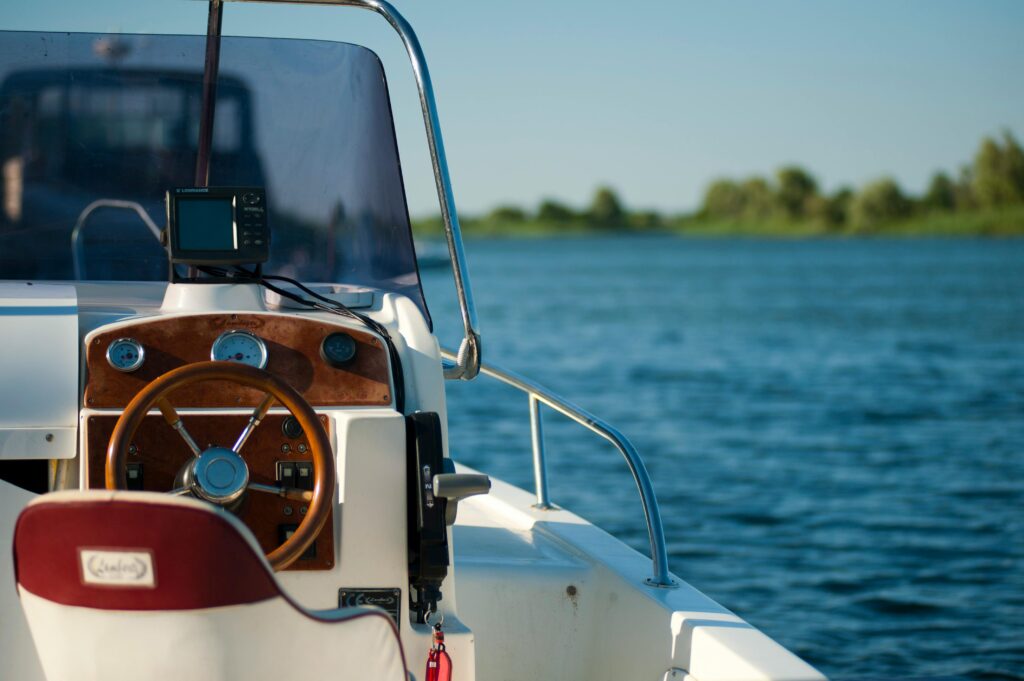 pexels-photo-1007836-1007836 A yacht steering wheel with a serene water view during a bright summer day offering leisure and adventure.